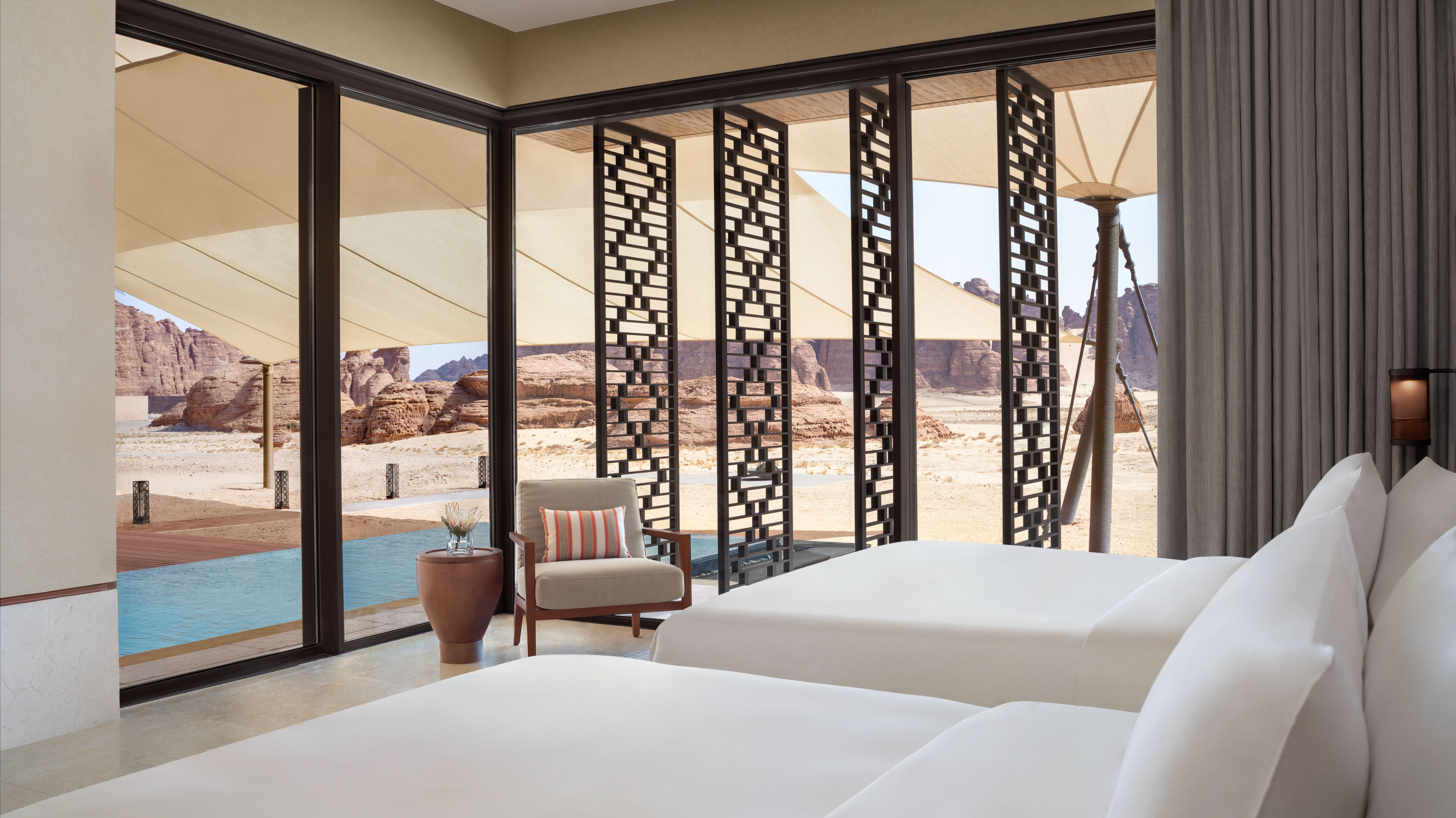 Beds near glass doors, desert view at Banyan Tree Alula Hotels & Resorts.